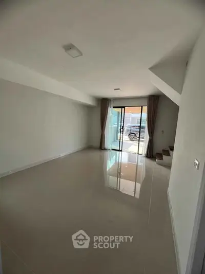 Spacious empty living room with large windows and glossy tiled floors