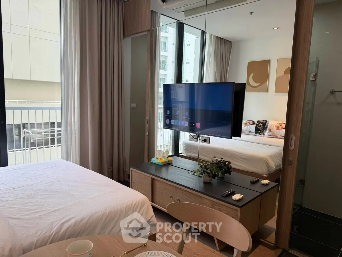 Modern bedroom with stylish decor and wall-mounted TV in a cozy apartment setting.