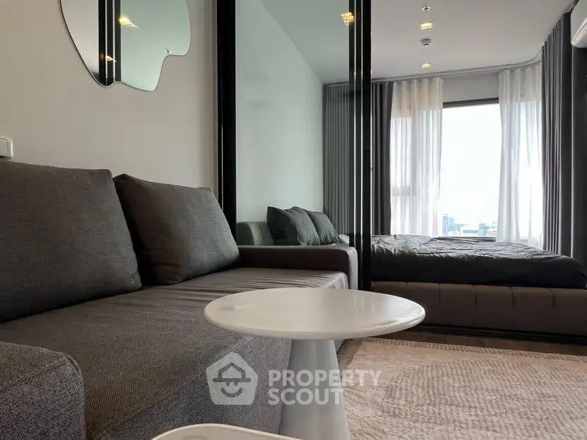 Modern studio apartment with sleek design and city view, featuring a cozy living area and comfortable bed.