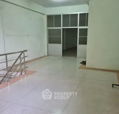 Spacious interior with tiled flooring and modern railing, ideal for versatile use.