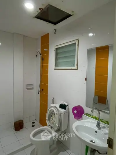 Modern bathroom with white tiles and orange accent wall, featuring a shower and sink.