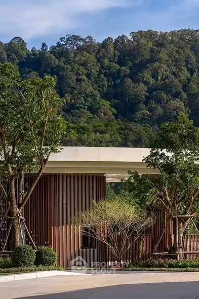 Stunning modern building entrance with lush greenery and scenic mountain backdrop.