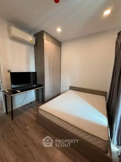 Cozy bedroom with modern furnishings and natural light, featuring a sleek wardrobe and air conditioning.