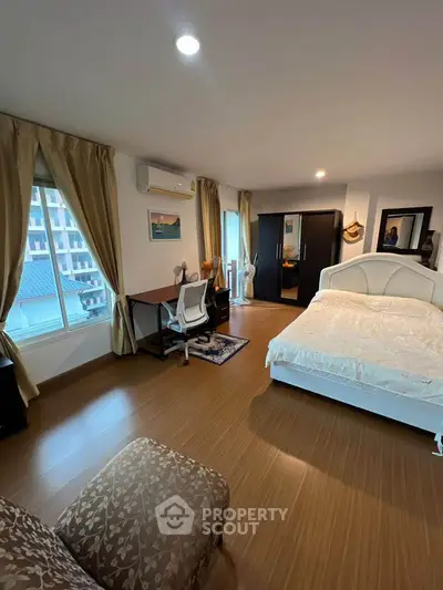 Spacious bedroom with modern furnishings and large windows offering natural light.