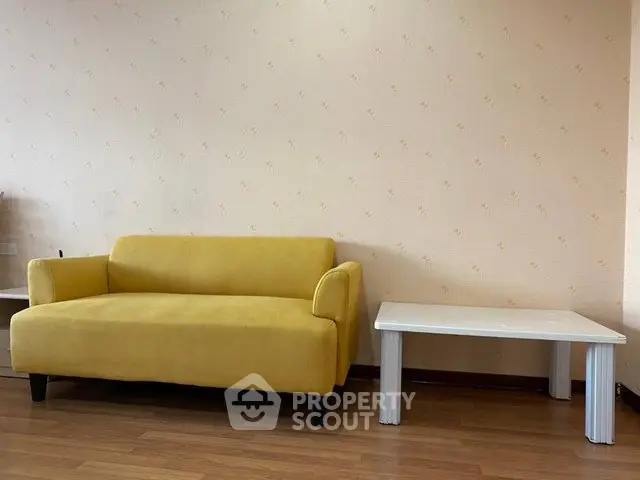 Cozy living room with a vibrant yellow sofa and sleek white coffee table on wooden flooring.