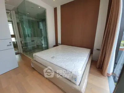Modern bedroom with glass-walled ensuite bathroom and large window for natural light.