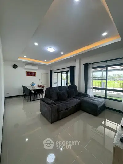 Spacious modern living room with large windows and elegant dining area, perfect for family gatherings.