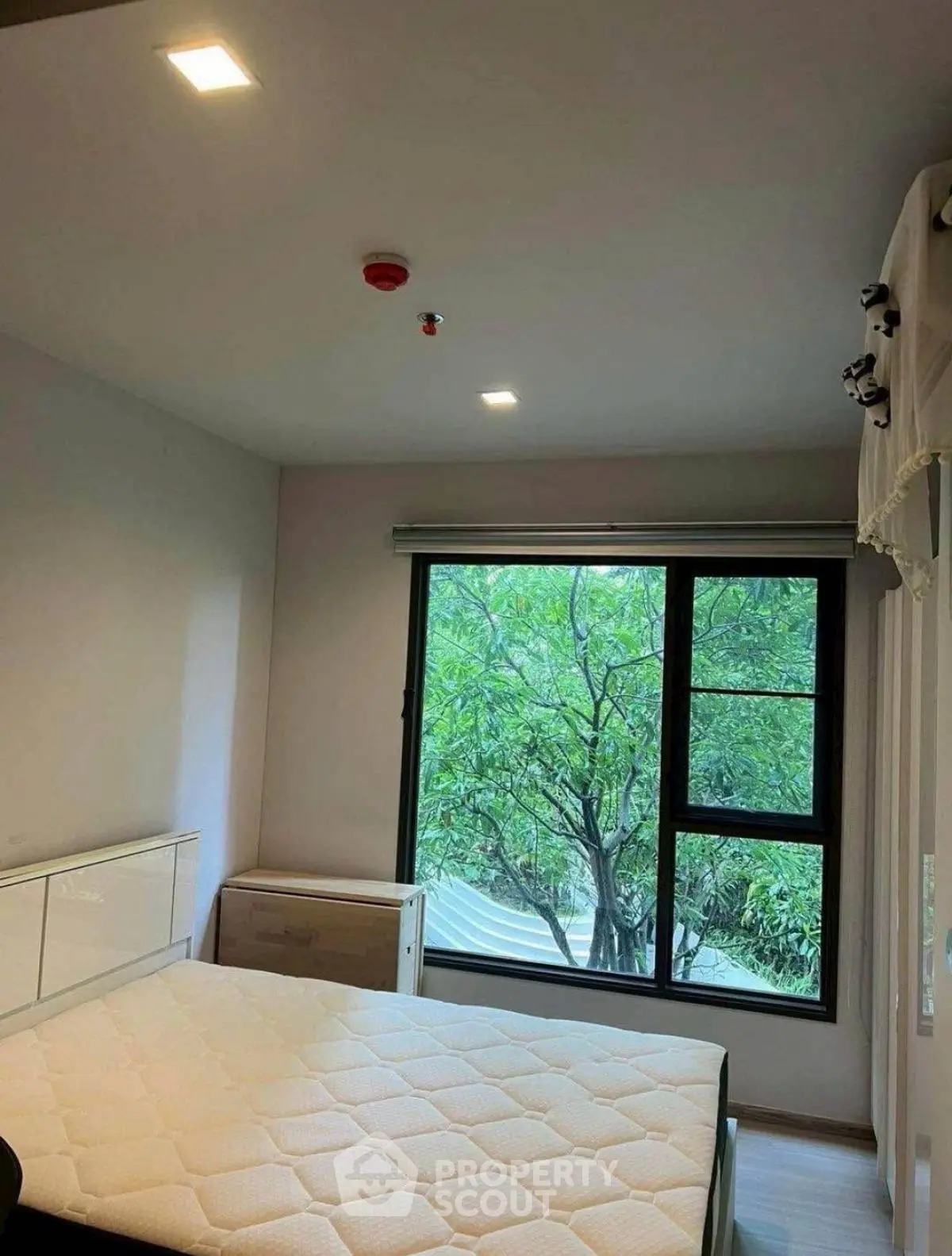 Cozy bedroom with large window and garden view, perfect for relaxation.