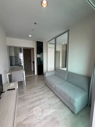 Modern living room with sleek design and natural light, featuring a comfortable gray sofa and stylish wooden flooring.