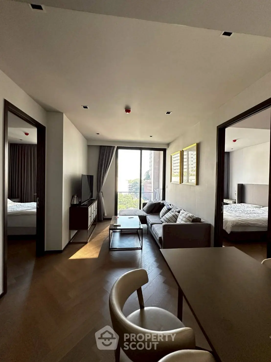 Modern living room with stylish furniture and natural light, connecting to two bedrooms with a scenic view.