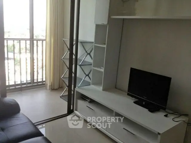 Modern living room with balcony view and sleek entertainment unit.