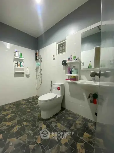 Modern bathroom with sleek design, featuring a toilet, shower, and stylish tile flooring.