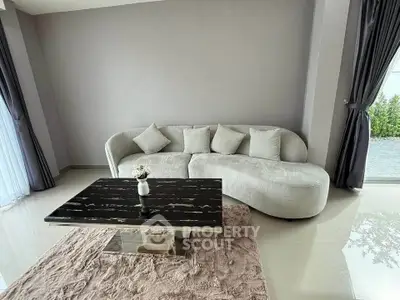 Elegant living room with modern curved sofa and sleek black marble coffee table.