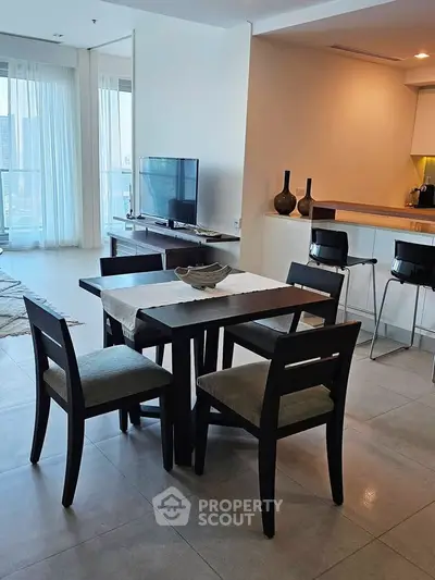 Modern dining area with elegant table and chairs, open layout to living room with natural light.