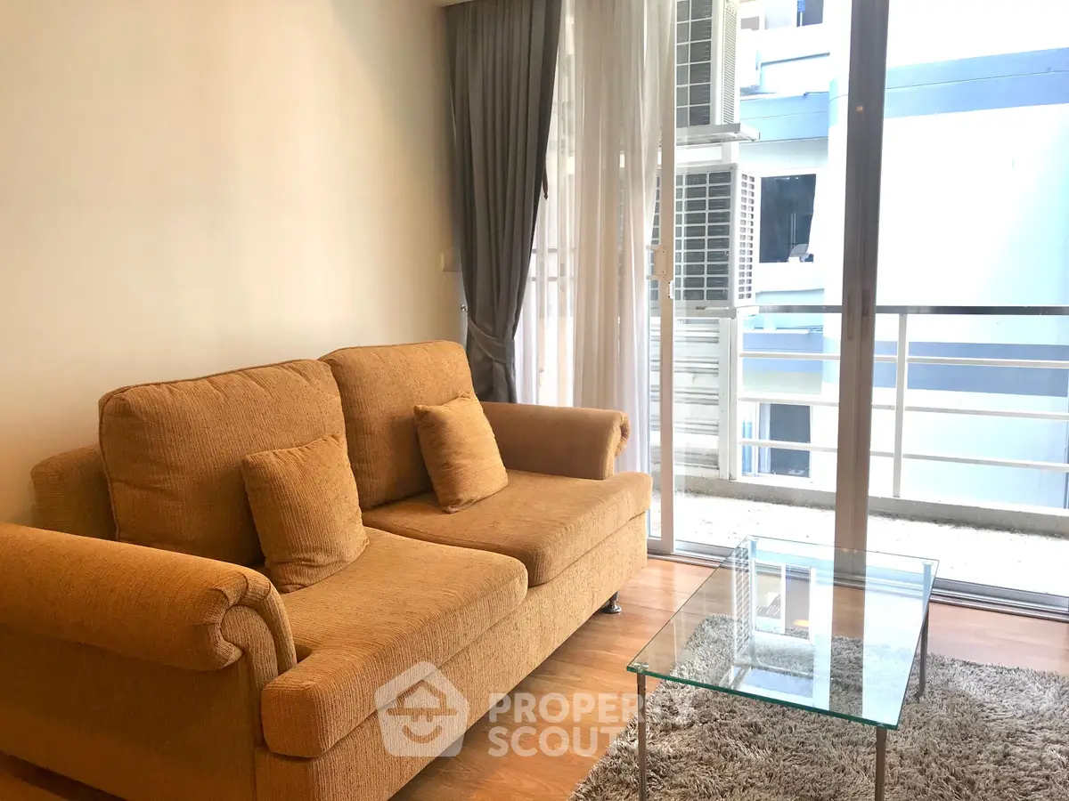 Cozy living room with plush sofa and glass coffee table, featuring floor-to-ceiling windows for natural light.