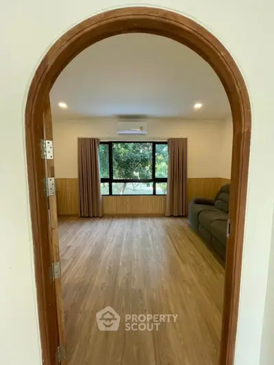 Spacious living room with large window and wooden flooring