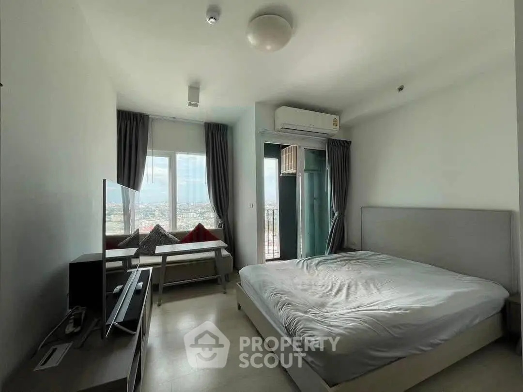 Modern bedroom with balcony and city view, featuring sleek furniture and natural light.
