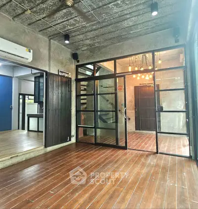 Modern industrial-style living room with wooden floors and glass partitions