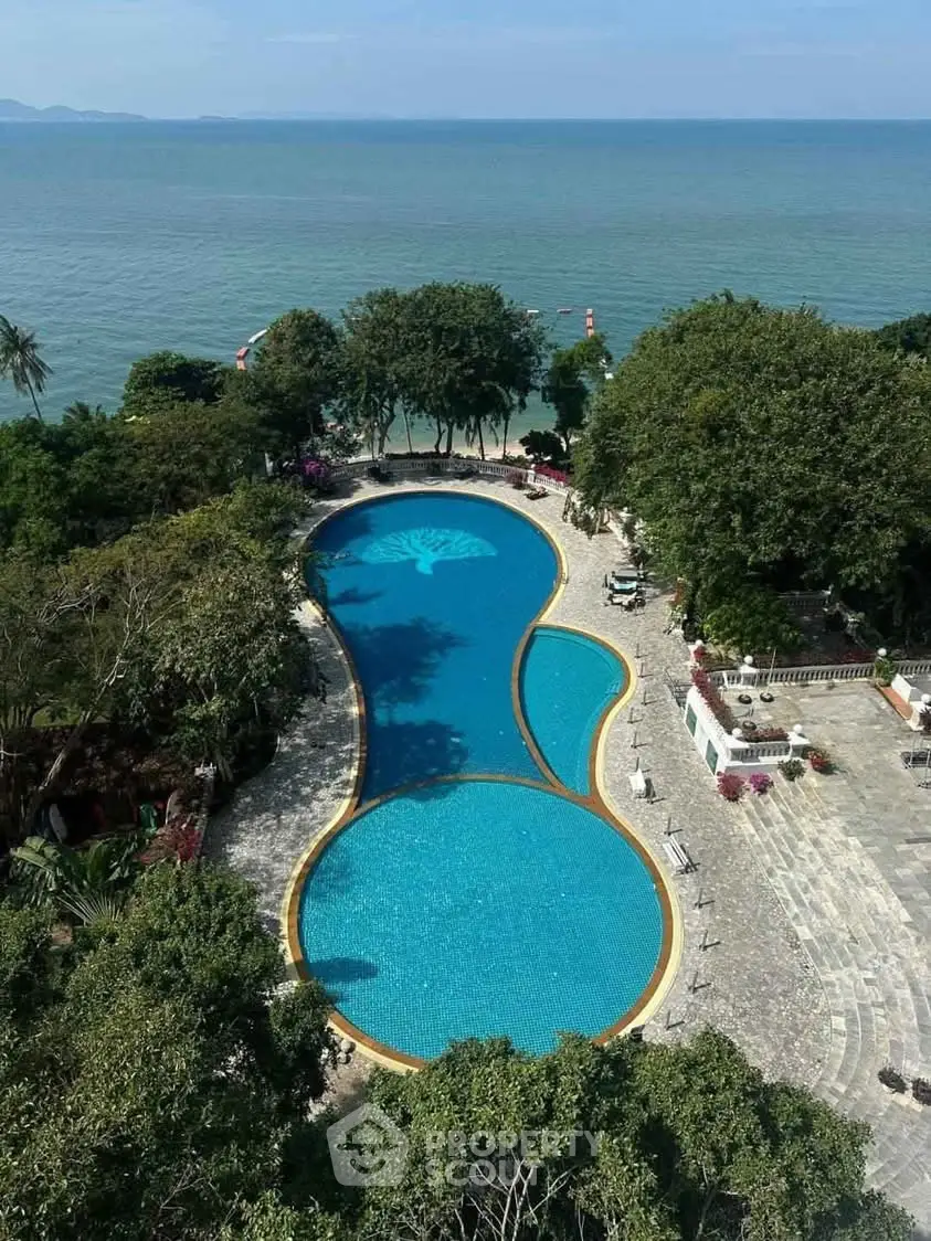 Stunning aerial view of a luxurious beachfront pool with ocean backdrop, perfect for relaxation and leisure.