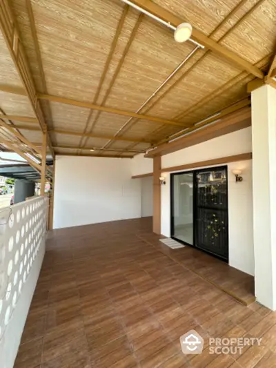 Spacious covered patio with wooden ceiling and tiled floor, perfect for outdoor relaxation.