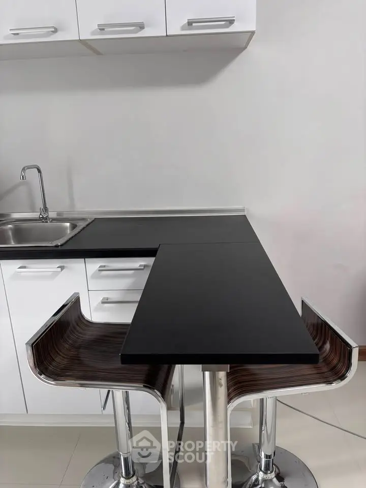 Modern kitchen with sleek black countertop and stylish bar stools