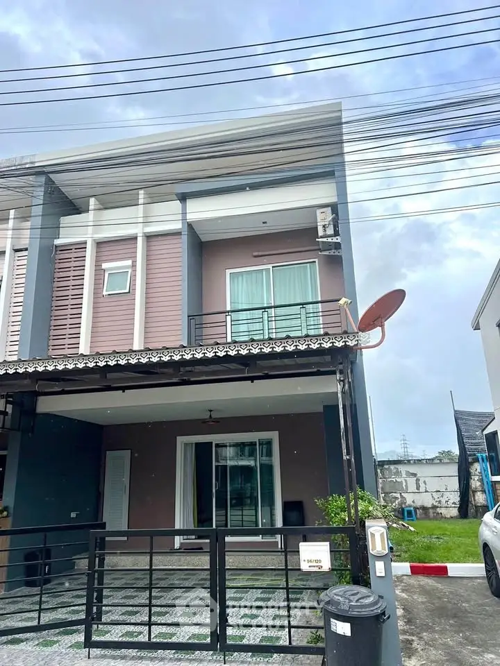 Modern two-story townhouse with balcony and gated driveway in suburban neighborhood.