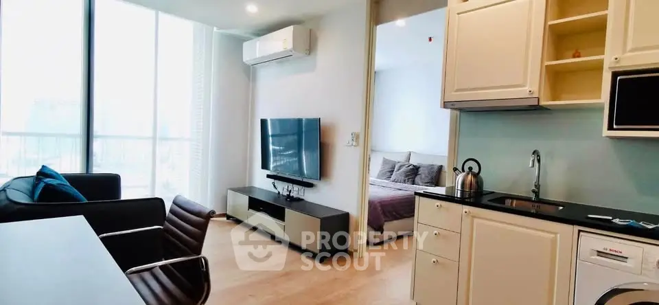 Modern apartment interior with open living room and kitchen, featuring sleek furniture and natural light.