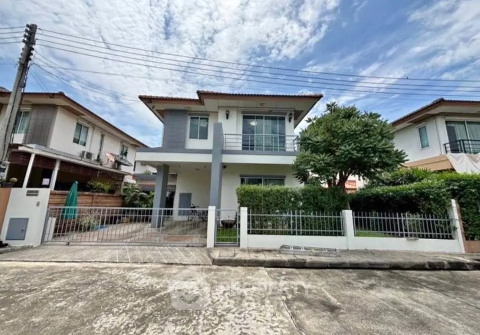 Modern two-story house with spacious front yard and lush greenery in suburban neighborhood.