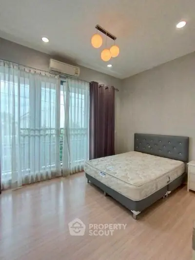 Spacious bedroom with large windows and modern lighting in a stylish apartment.