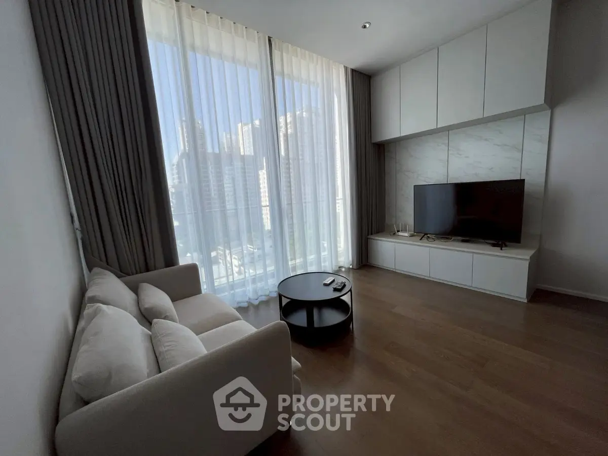 Modern living room with large windows, cozy sofa, and sleek TV setup.