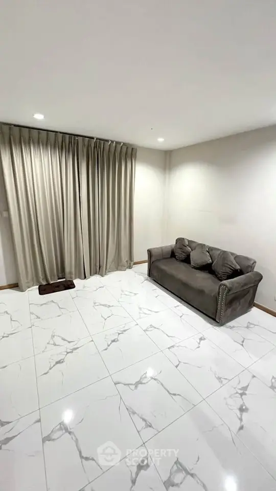 Spacious living room with elegant marble flooring and cozy sofa, perfect for relaxation.