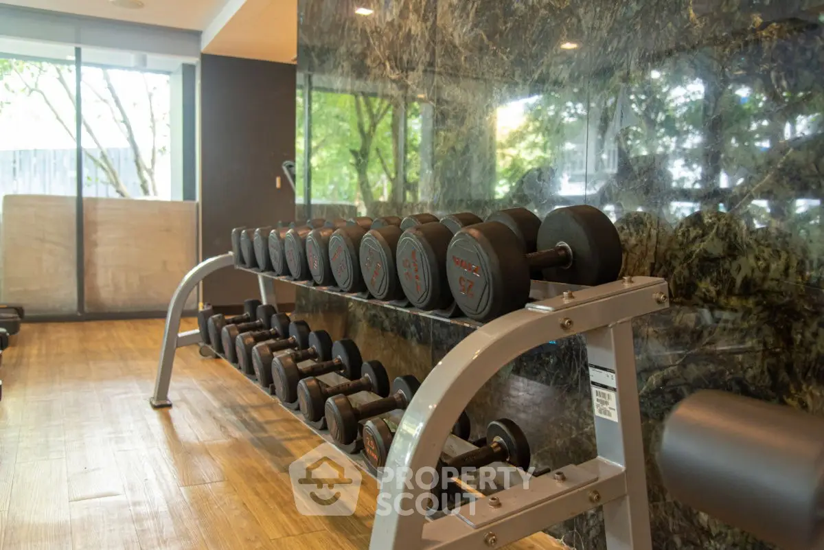 Modern gym with dumbbells and mirrored wall in luxury real estate property.