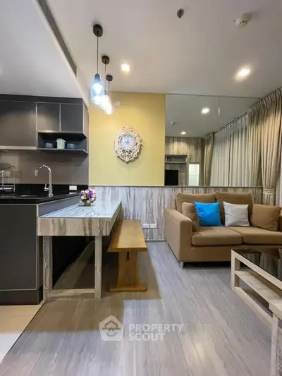 Modern living room with stylish decor and open kitchen layout, featuring cozy seating and elegant lighting.