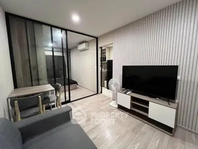 Modern living room with glass partition, sleek TV setup, and cozy dining area in stylish apartment.