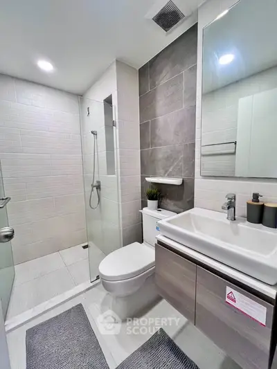 Modern bathroom with sleek design, featuring glass shower and stylish fixtures.