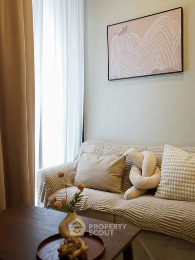 Cozy living room with stylish decor and natural light, featuring a comfortable sofa and elegant wall art.
