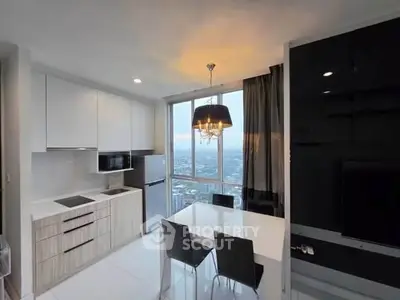Modern kitchen with dining area and city view, featuring sleek cabinetry and elegant lighting.