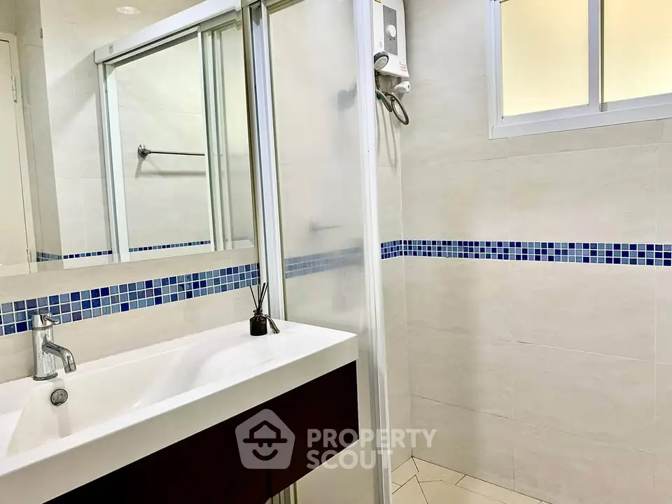 Modern bathroom with sleek sink and shower in stylish apartment.