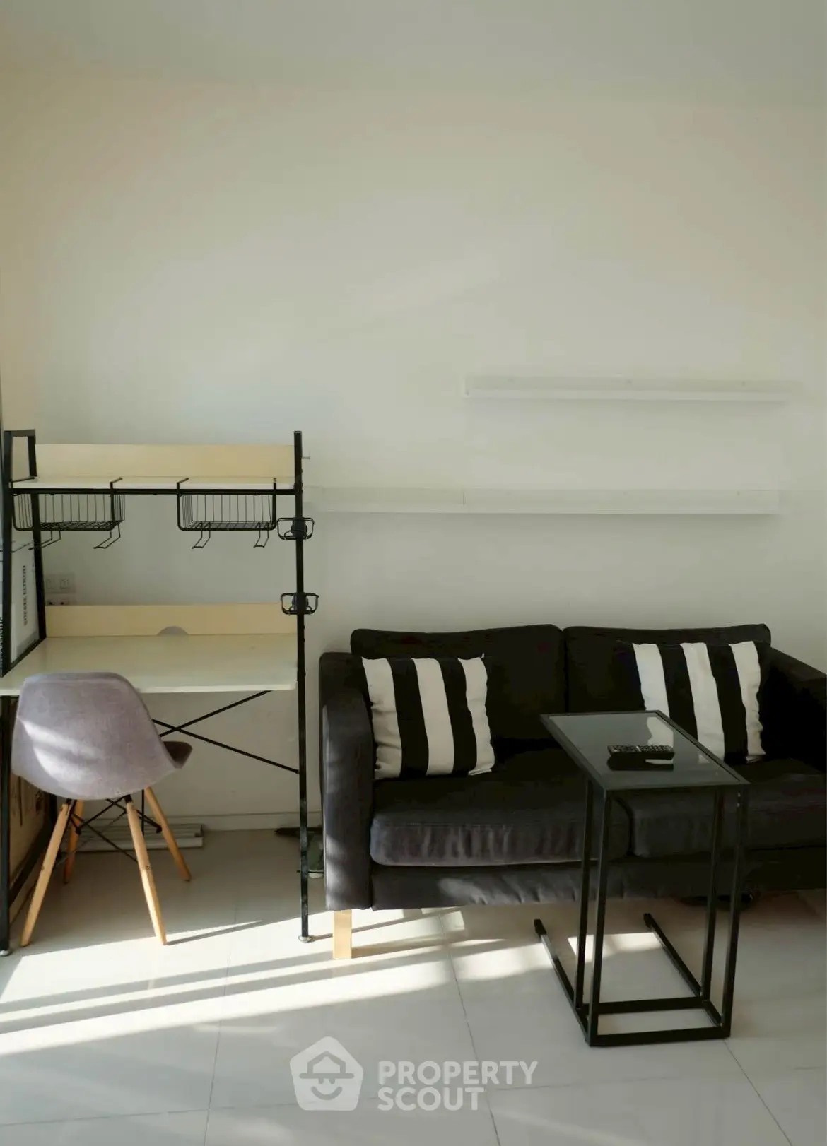 Modern living room with sleek black sofa, stylish desk, and minimalist decor.