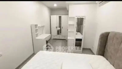 Spacious bedroom with modern white furniture and cozy bed in a minimalist design.