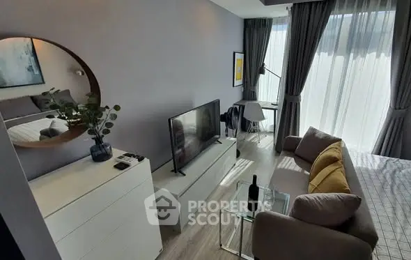 Modern living room with stylish decor and natural light, featuring a cozy seating area and sleek TV setup.