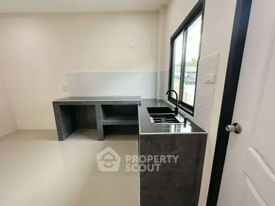 Modern kitchen with sleek countertops and large window for natural light.