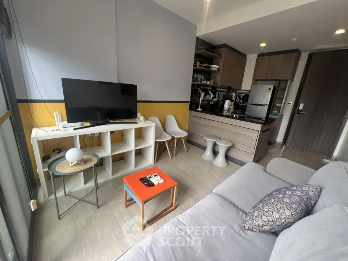 Modern living room with open kitchen, stylish decor, and cozy seating area.