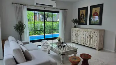 Elegant living room with pool view, featuring stylish furniture and large windows for natural light.