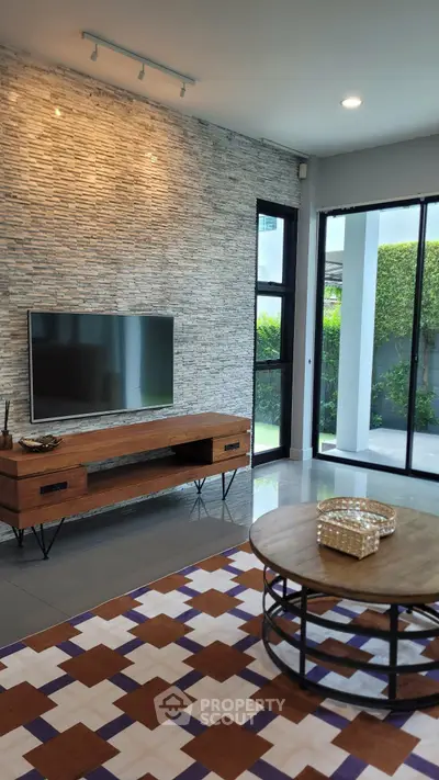 Modern living room with stylish decor, large TV, and natural light from floor-to-ceiling windows.