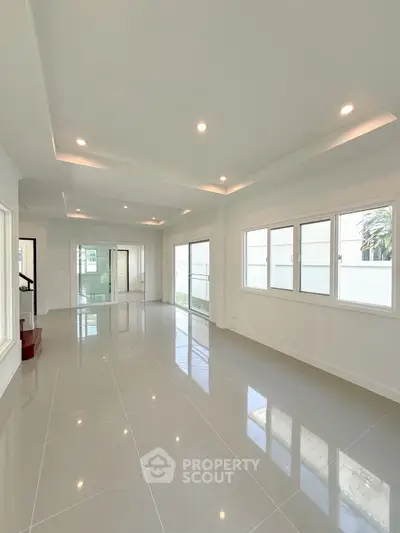Spacious modern living room with large windows and glossy tiled floors