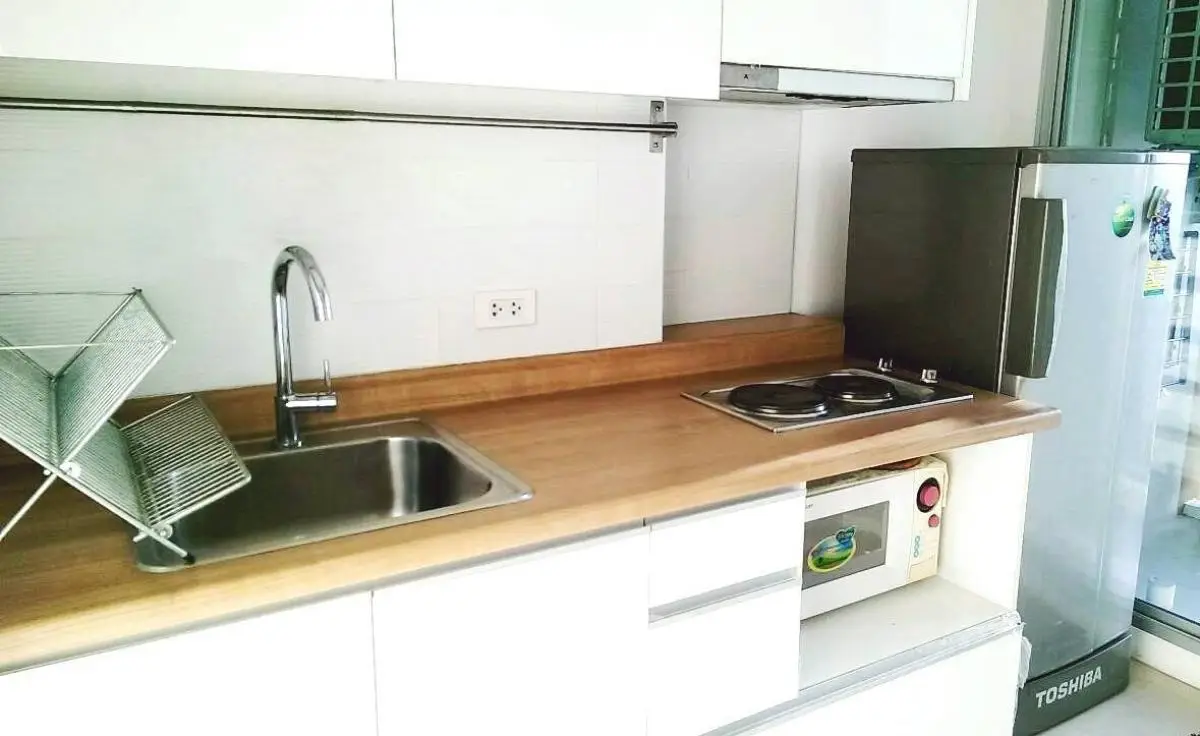 Modern kitchen with sleek countertop, electric stove, and compact fridge in a stylish apartment.