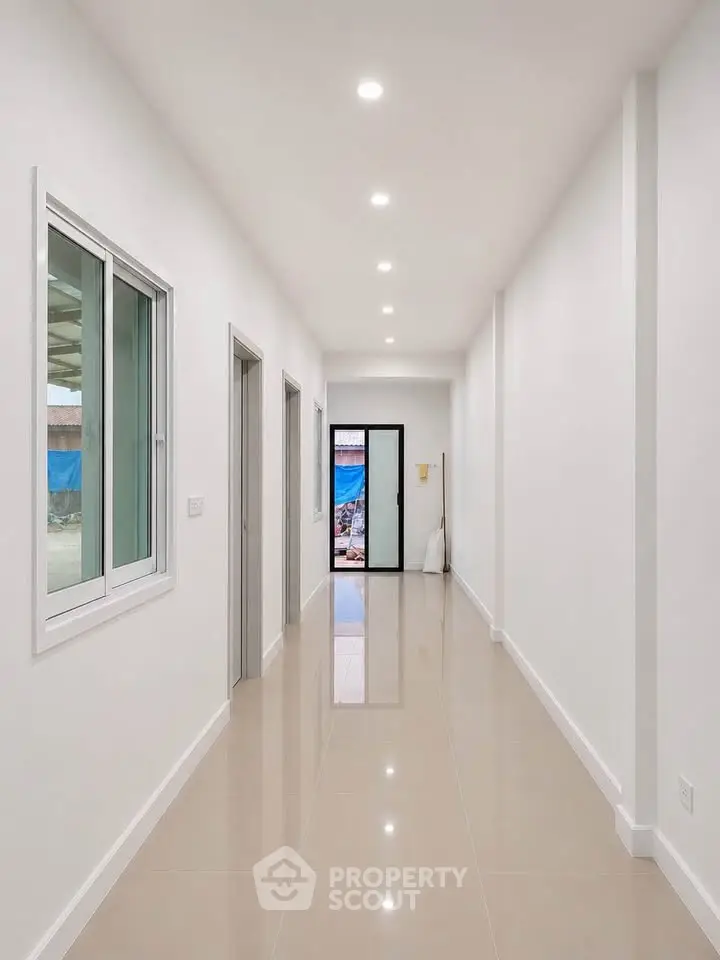 Bright and spacious corridor with glossy tiled flooring and modern lighting.