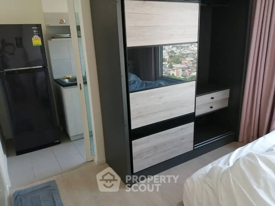 Modern bedroom with sleek wardrobe and view of compact kitchen area.