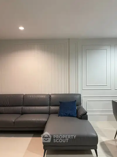 Modern living room with sleek gray leather sectional sofa and elegant wall paneling.